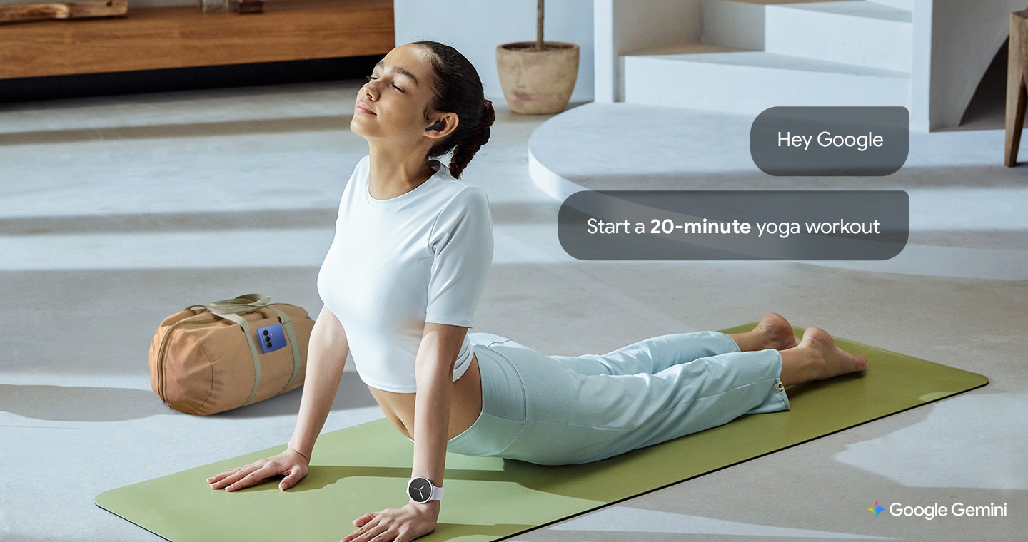 A woman wearing Galaxy Watch8 and Galaxy Buds3 FE stretches on a yoga mat with a gym bag beside her. While stretching, she uses voice wake-up to activate Gemini by saying “Hey Google” and asks it to set a timer.