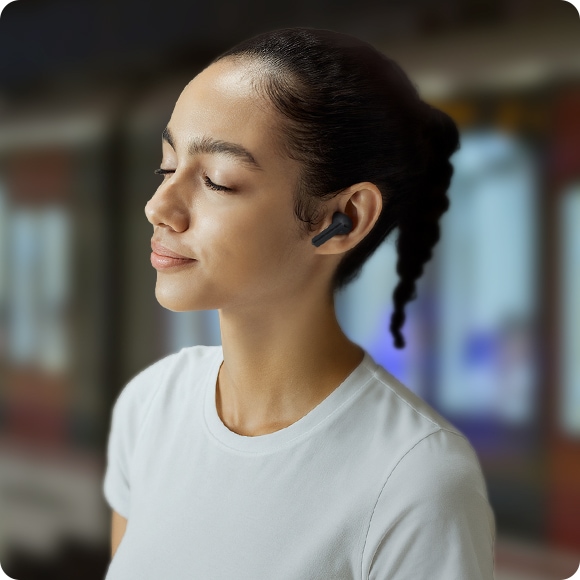 A woman wearing Black Galaxy Buds3 FE in an urban setting.
