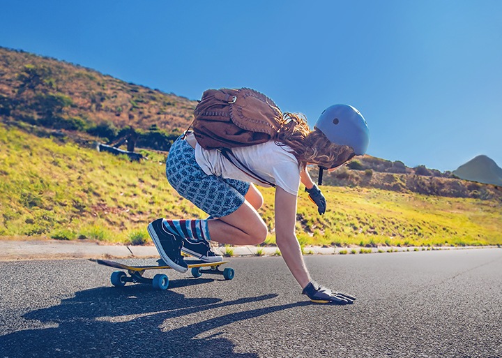 Longboarder is riding down a long, empty road while captured by the photographer who is also longboarding down behind. On the captured photo, a line down the screen divides the photo into left and right, which show the difference between stabilized and unstabilized shots. 
