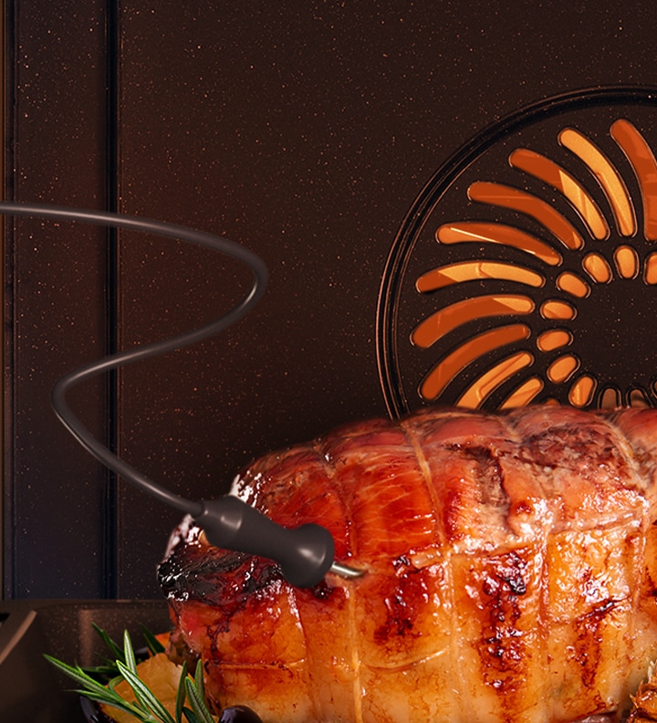 Shows a Food Probe inserted into a joint of meat that is being roasted.