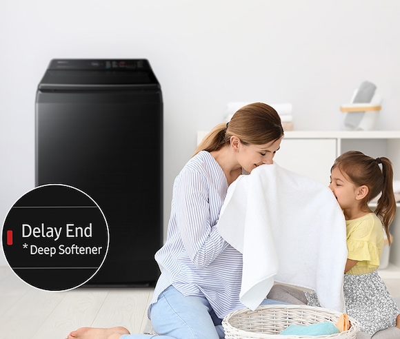 On the side of the washing machine, a woman is smelling a towel with her daughter. The towel was washed using the Deep Softener of the Delay End course.