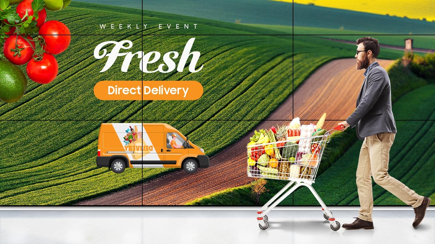 A crop advertisement is displayed on the Video Wall, and a man is pushing a cart in front of it.