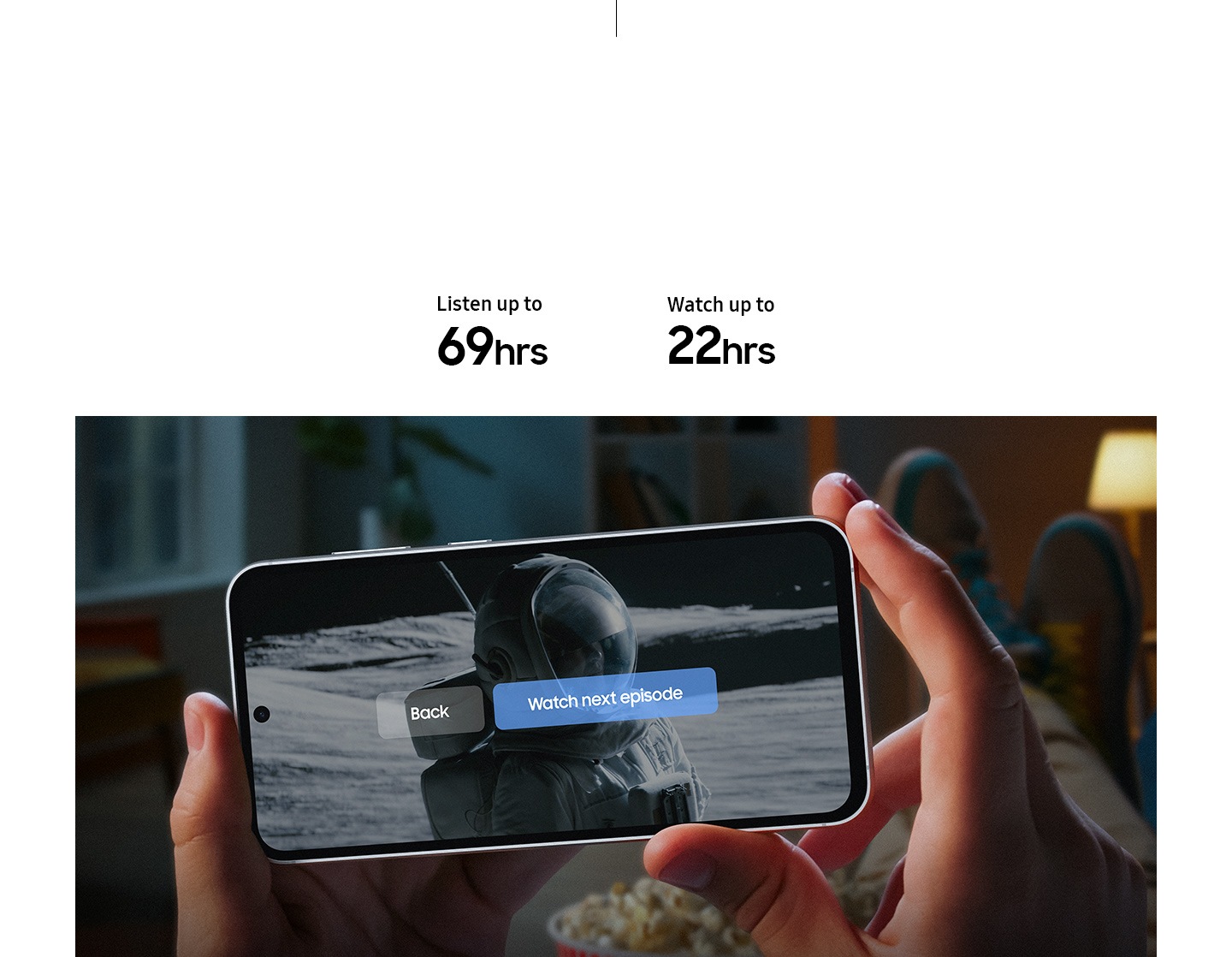 Dos manos sostienen un Galaxy S23 FE que muestra el final de una serie en pantalla. Un subtítulo dice Ver el siguiente episodio, atrás para destacar que el dispositivo tiene batería de larga duración. El texto dice Escucha hasta 69 horas, Mira hasta 22 horas.