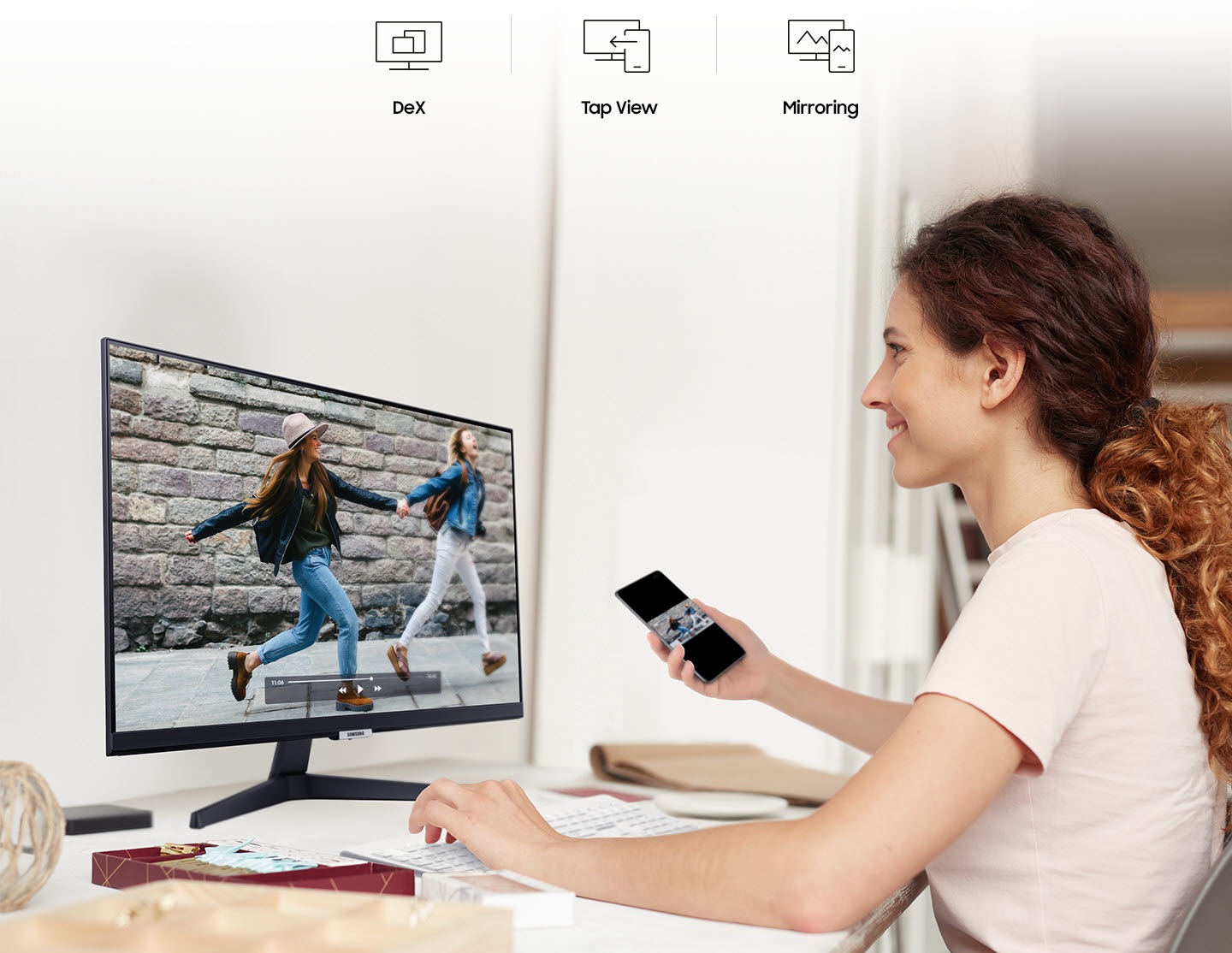 A smiling woman mirrors videos from her phone to her monitor. At the top are the DeX, Tap View, and Mirroring icons.