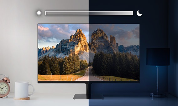 Samsung M5 Smart Monitor sits on top of a desk and is split into left and right sides. The left side is brightly lit while the right side is very dark. Above the screen is a slider icon with a sun on the left and a moon on the right.