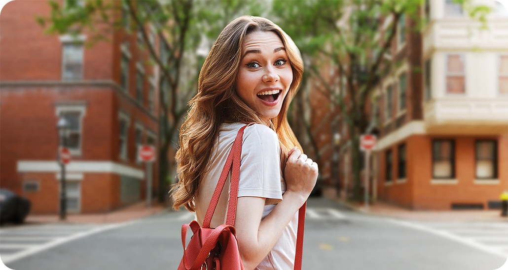 A shot of a woman standing in a courtyard taken with Samsung Galaxy A13 2MP Depth Camera with the Live Focus On is activated. The buildings in the background are blurred.