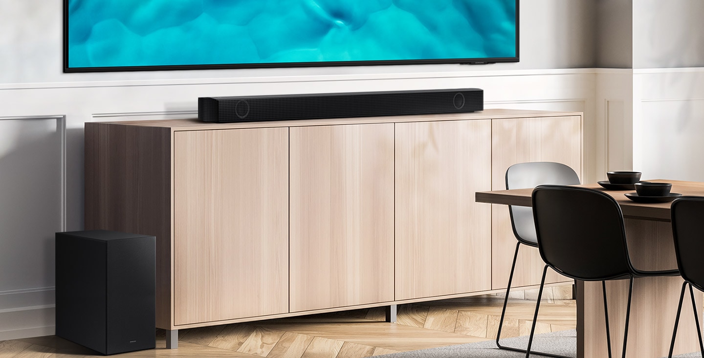 Samsung B series Soundbar and subwoofer are positioned with Crystal UHD TV on living room cabinet.