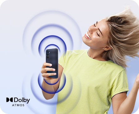 A woman holding a Galaxy A25 5G in Blue Black is dancing to music that is coming her device, shown in concentric circles that start at the top and bottom of the device. To the left, Dolby Atmos logo is shown.