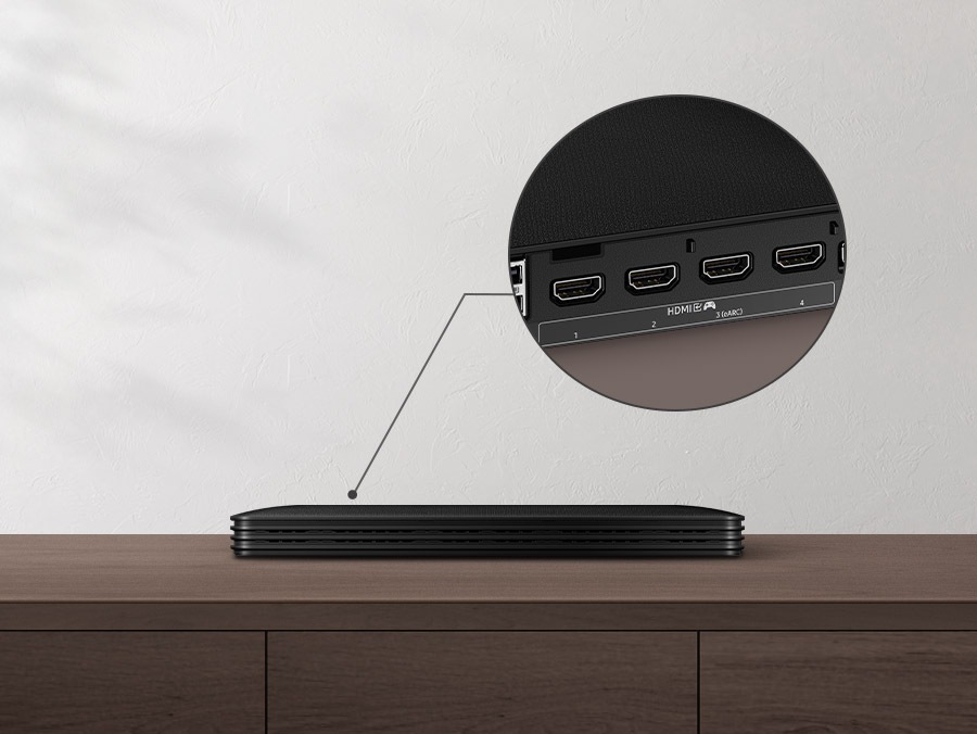 The One Connect Box is on a table. Its various ports on the back are zoomed in. The Attachable Slim One Connect box is attached to the Neo QLED TV.