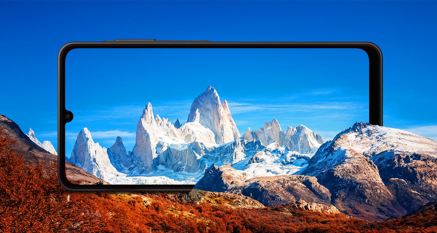 A large Galaxy A06 5G is positioned horizontally between rocky mountains. The screen frames the snowcapped mountains against a blue sky.