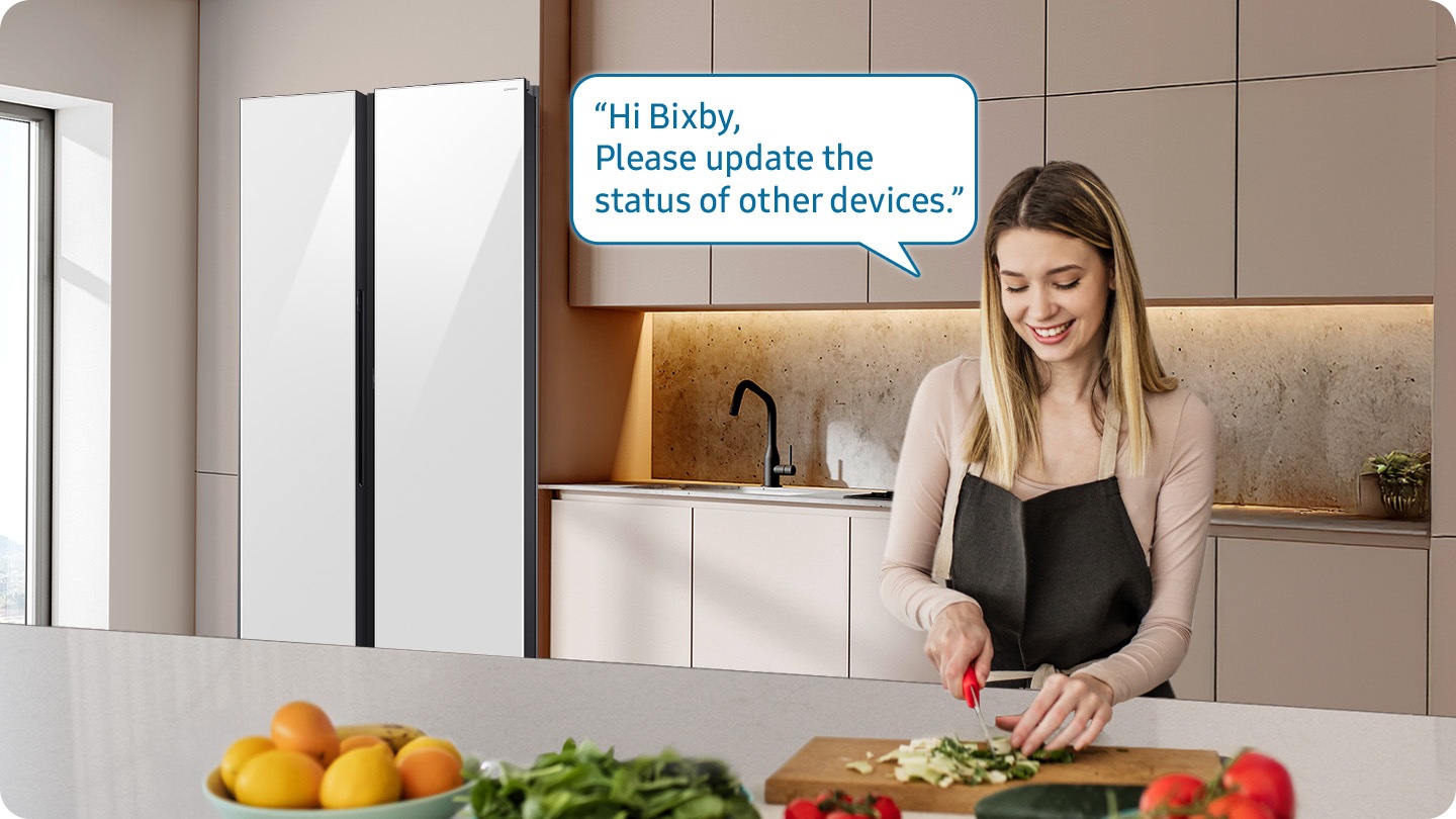 Shows a person preparing food while controlling the refrigerator using a Samsung Bixby. “Hi Bixby, Please update the status of other devices."