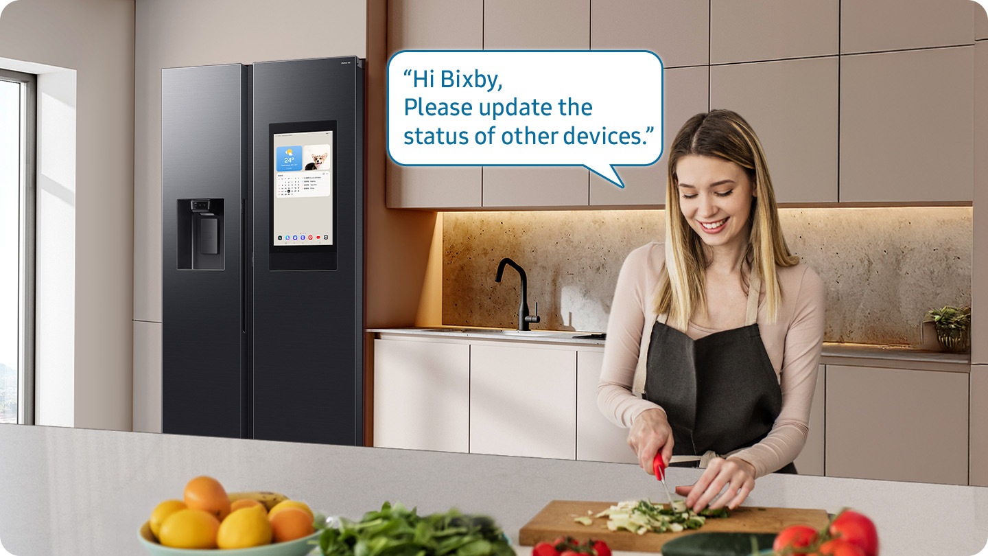 Shows a person preparing food while controlling the refrigerator using a Samsung Bixby. “Hi Bixby, Please update the status of other devices.”