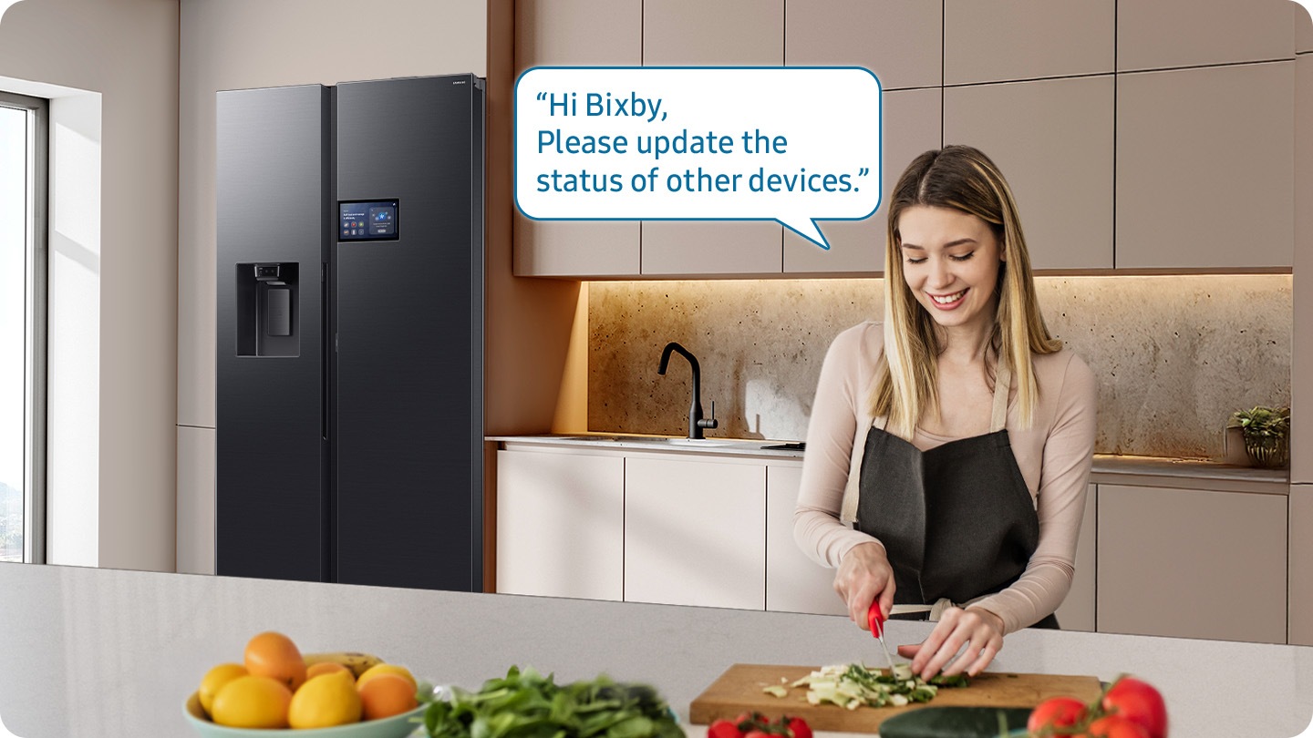 Shows a person preparing food while controlling the refrigerator using a Samsung Bixby. “Hi Bixby, Please update the status of other devices.”