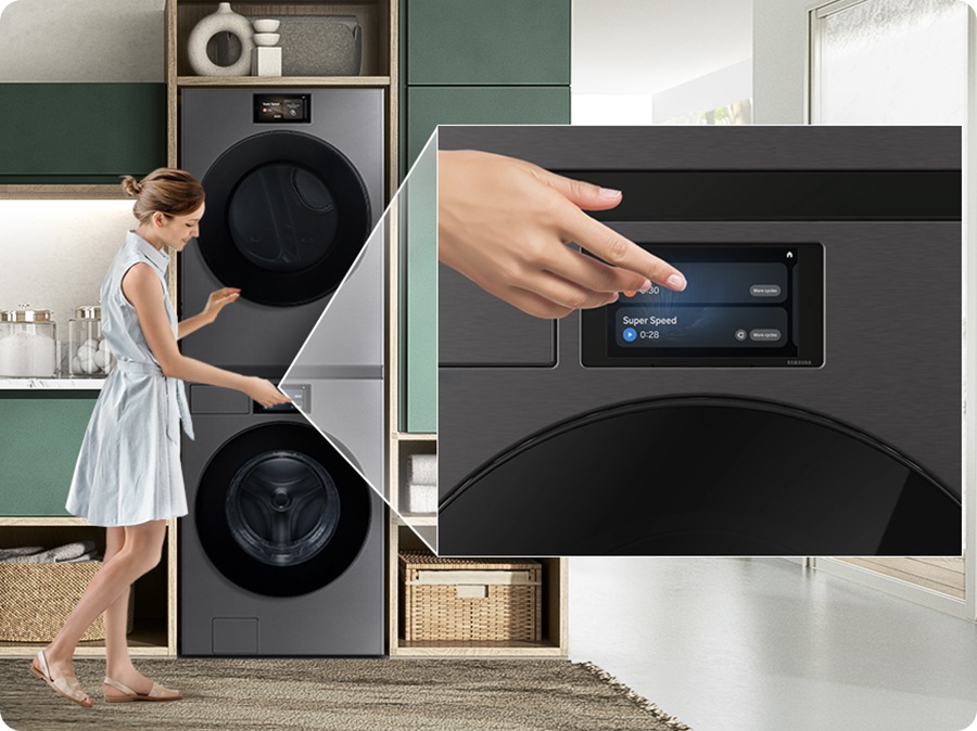 A washing machine and dryer are stacked vertically in a laundry room. A woman touches the washing machine screen to control the dryer. The dryer then zooms in, showing the laundry being dried inside.