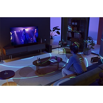 A man watches TV in a living room. SpaceFit Sound Pro sends out blue rings to analyze the space and optimize sound.