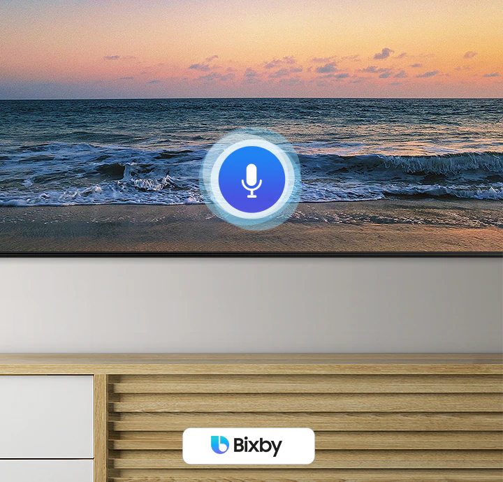 A microphone icon overlays a beach sunset TV screen image, demonstrating QLED TV voice assistant feature.