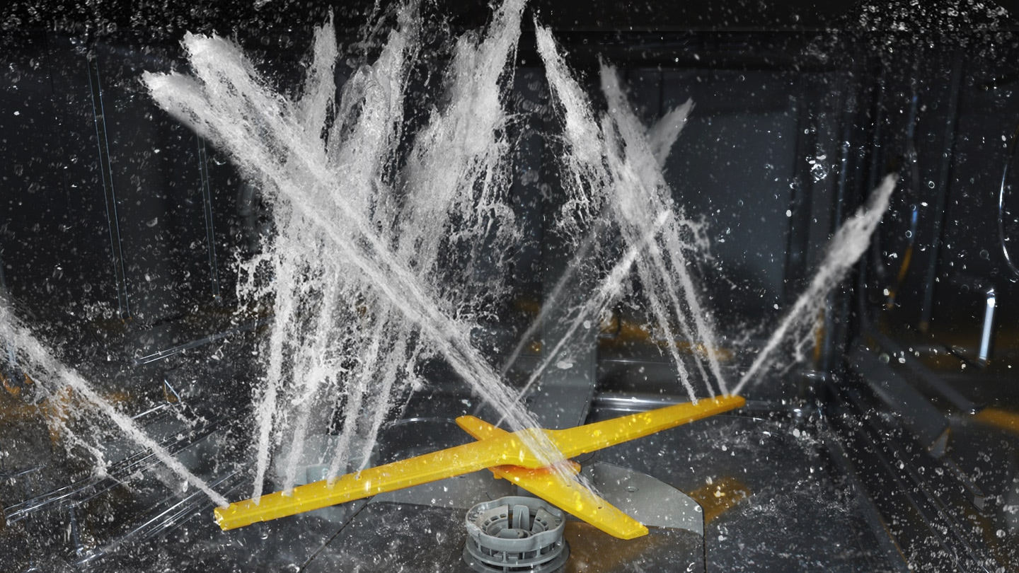 Montre les deux bras rotatifs du système WaterJet Clean™ pulvérisant de puissants jets d’eau dans plusieurs directions.