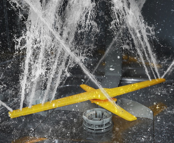 Montre les deux bras rotatifs du système WaterJet Clean™ pulvérisant de puissants jets d’eau dans plusieurs directions.