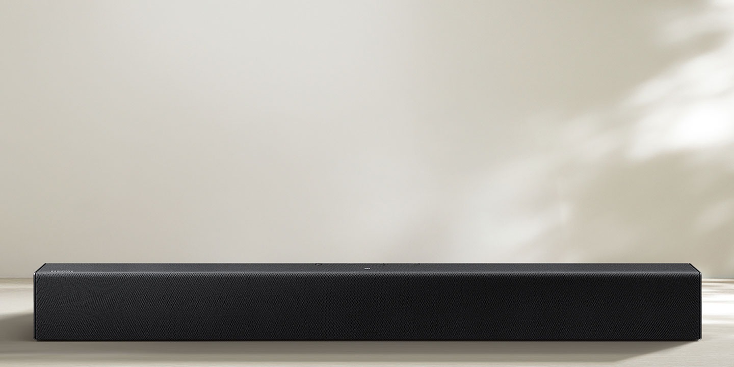 Une barre de son Samsung diffuse du son et des basses qui ondulent sur le sol.