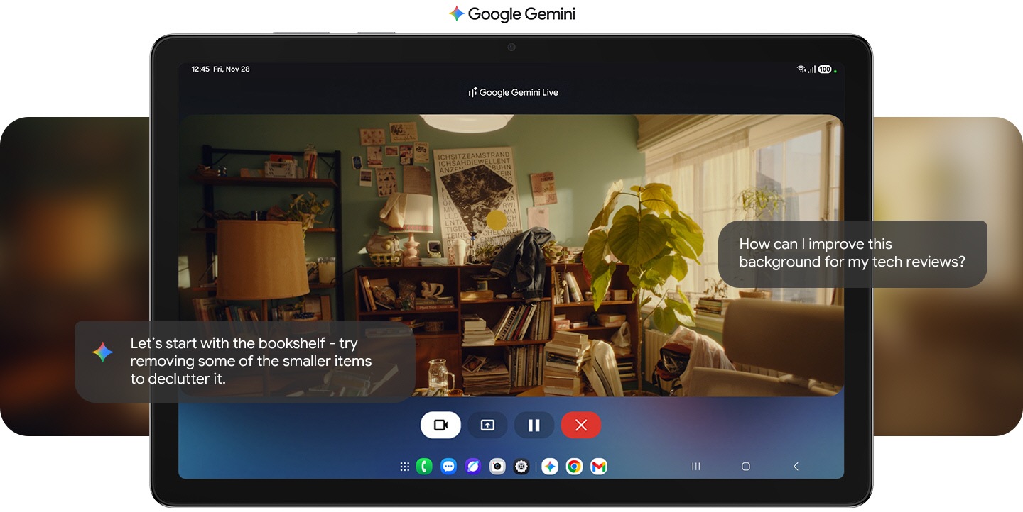 On the screen of a horizontally placed Galaxy Tab A11+, the Gemini Live feature is activated. In response to the inquiry 'How can I improve this background for my tech reviews?', Gemini suggests, 'Let's start with the bookshelf - try removing some of the smaller items to declutter it'. The background in question fills the screen, seemingly the interior of a studio or an apartment.