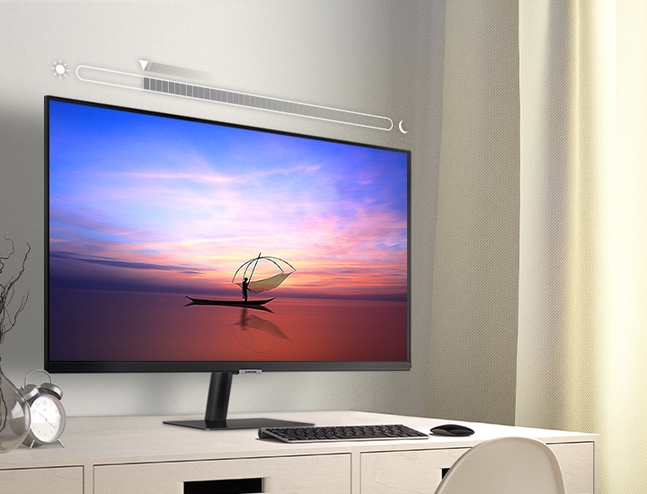 A 32 inch Smart Samsung M7 Monitor placed on a home work desktop with a brightness metre superimposed above it, showcasing the M7 Monitor's adaptive picture function.