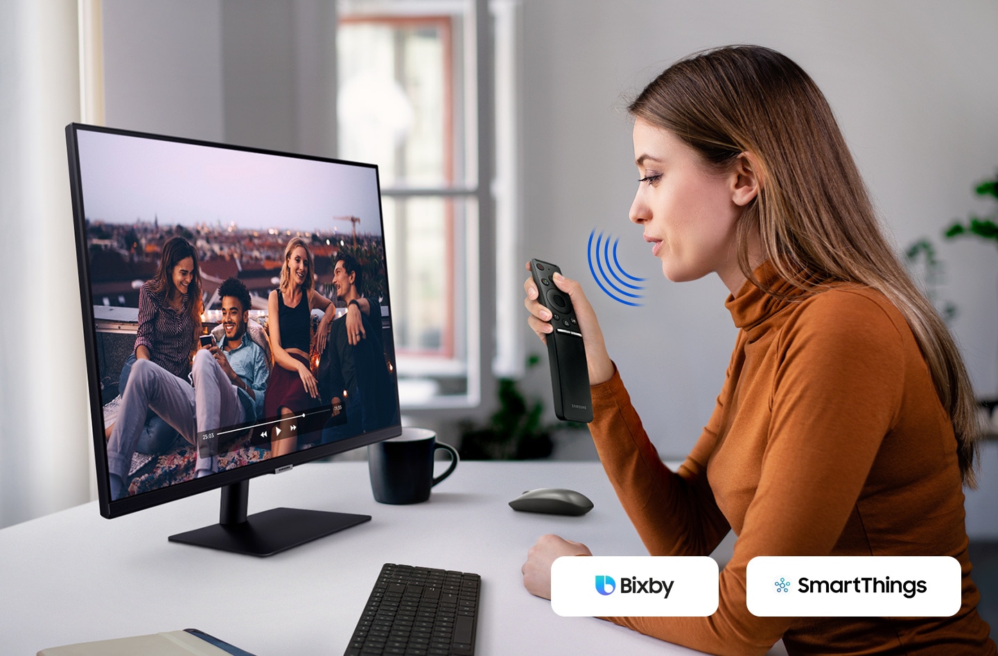 A lady speaking to the 32 inch Samsung M7 Monitor's remote control equipped with the Samsung Bixby voice assistant and SmartThings app.