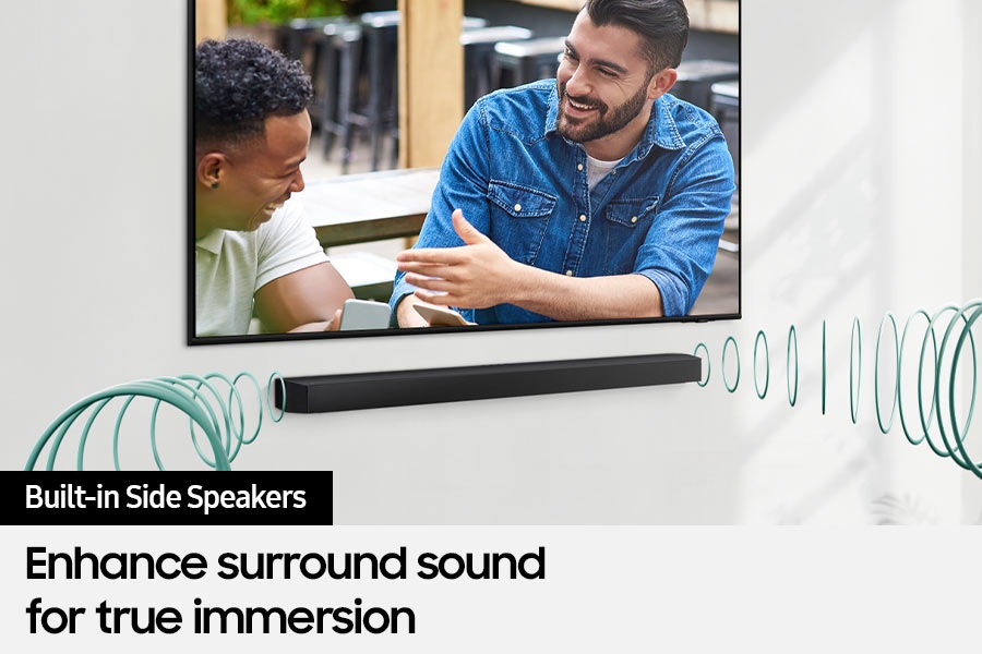 A TV shows a scene of two men talking, with the built-in side speakers in the Soundbar enhancing surround sound.