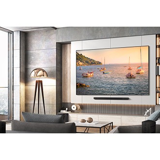A 98 inch QLED TV hangs on the wall, showcasing a picturesque view of numerous boats sailing on the sea. Below the TV, a soundbar is installed.