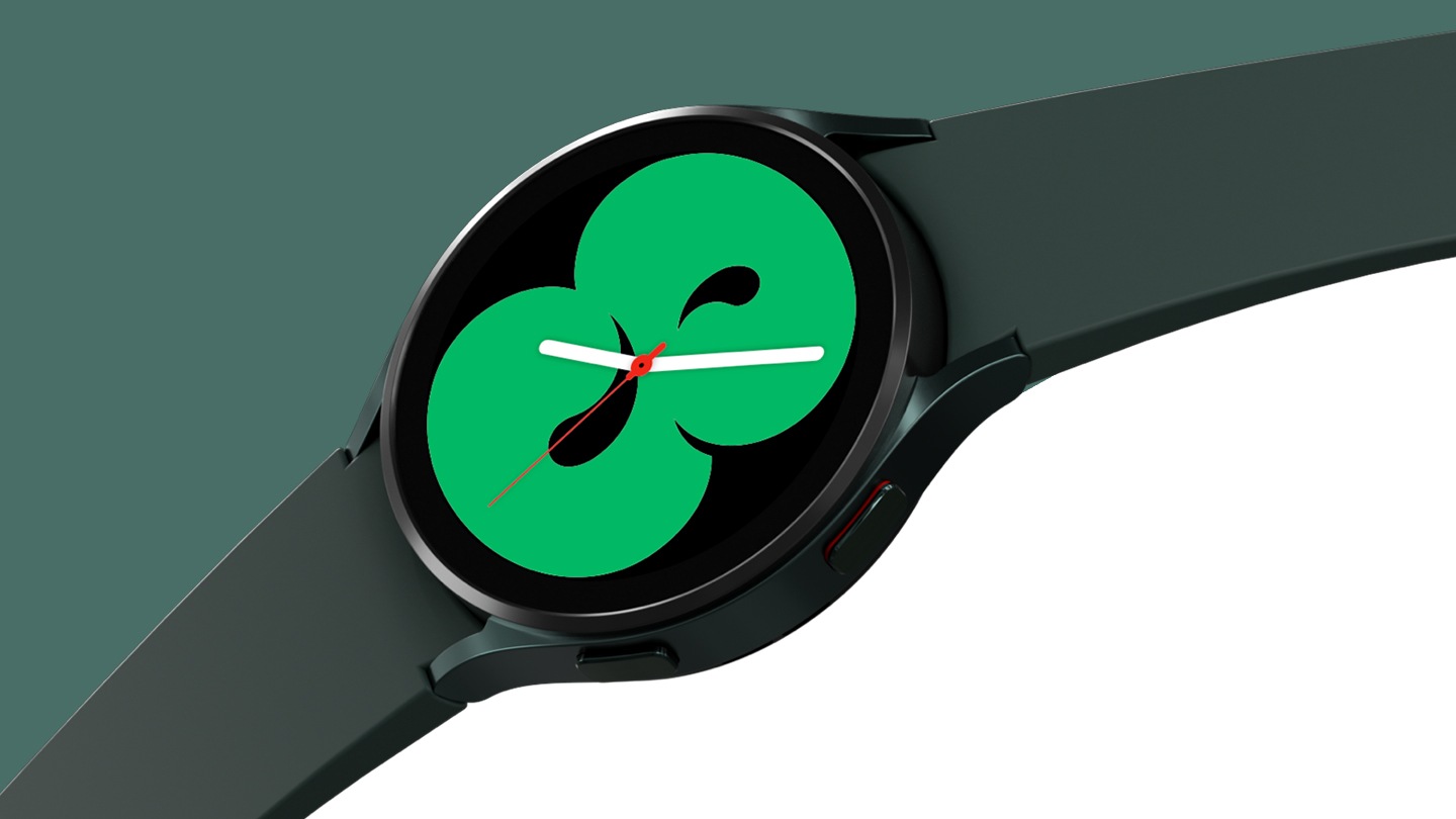 A green Galaxy Watch4 is displayed with a band that is spread wide. The watch face shows one of the designs that displays the time in a green color.