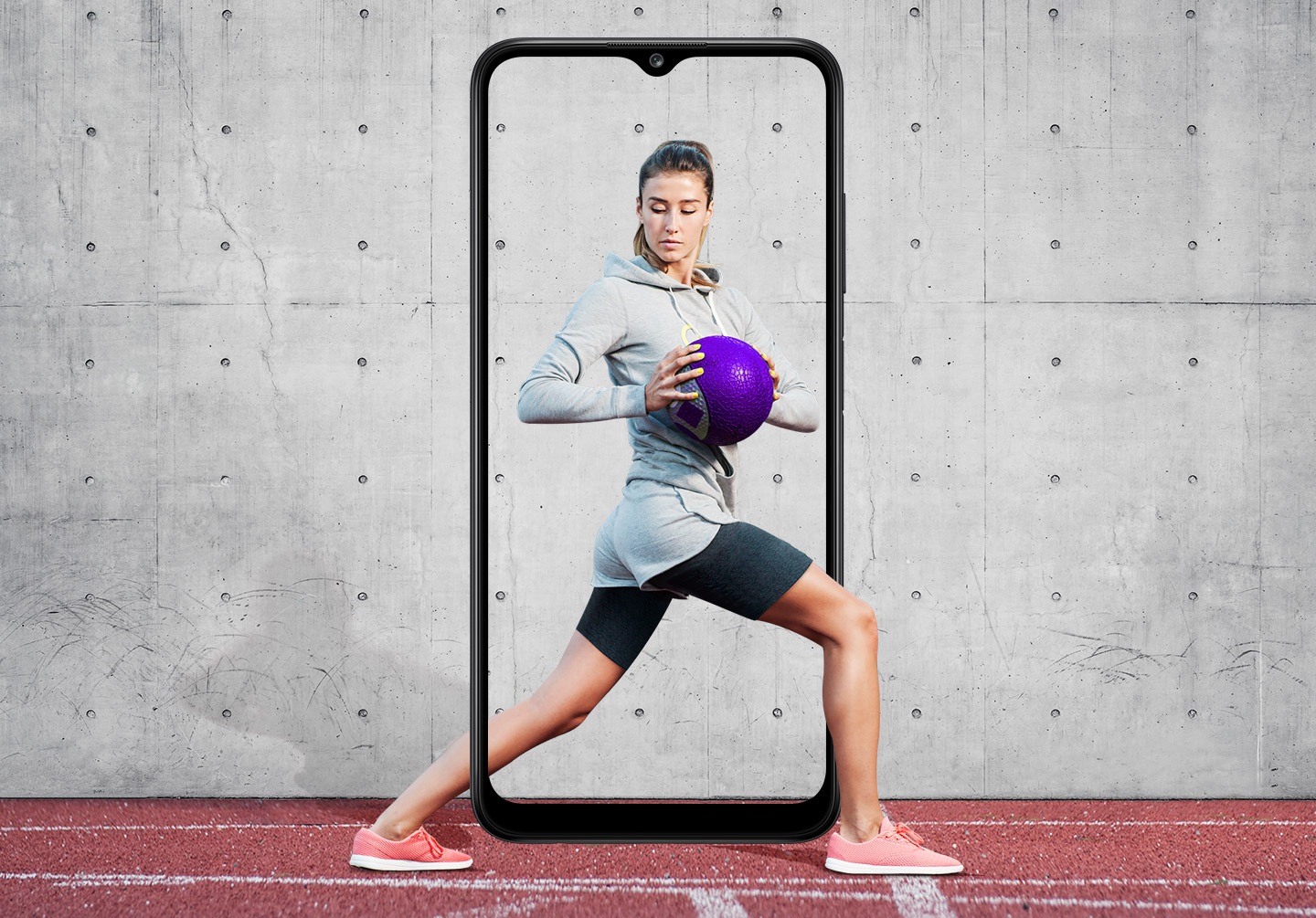 A woman is shown performing a standing torso twist with her legs in a lunge position while holding a purple medicine ball. The Galaxy A03s's slim bezel frames her entire body, with her feet and part of her calf outside it.