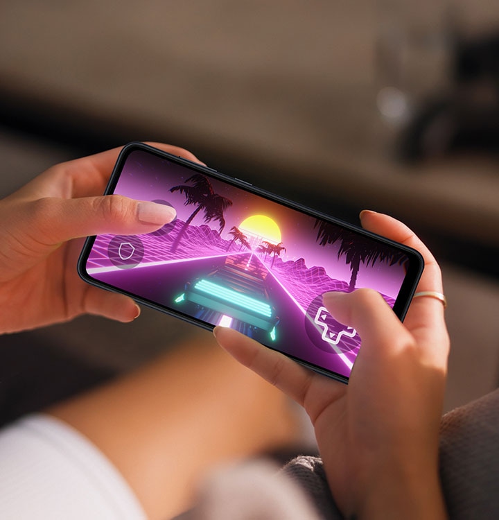 Two hands holding a Samsung Galaxy A05 shows racing gameplay on-screen.