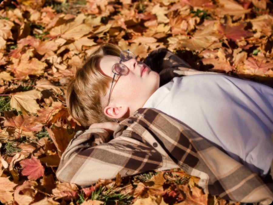 Image of a little boy laying on the ground covered in fall leaves. Several differents points are detected, including the boy's face, hair, clothes and leaves, and then upscaled to 4K resolution, along with the rest of the image. The result is a much sharper image where subtle details are visible.