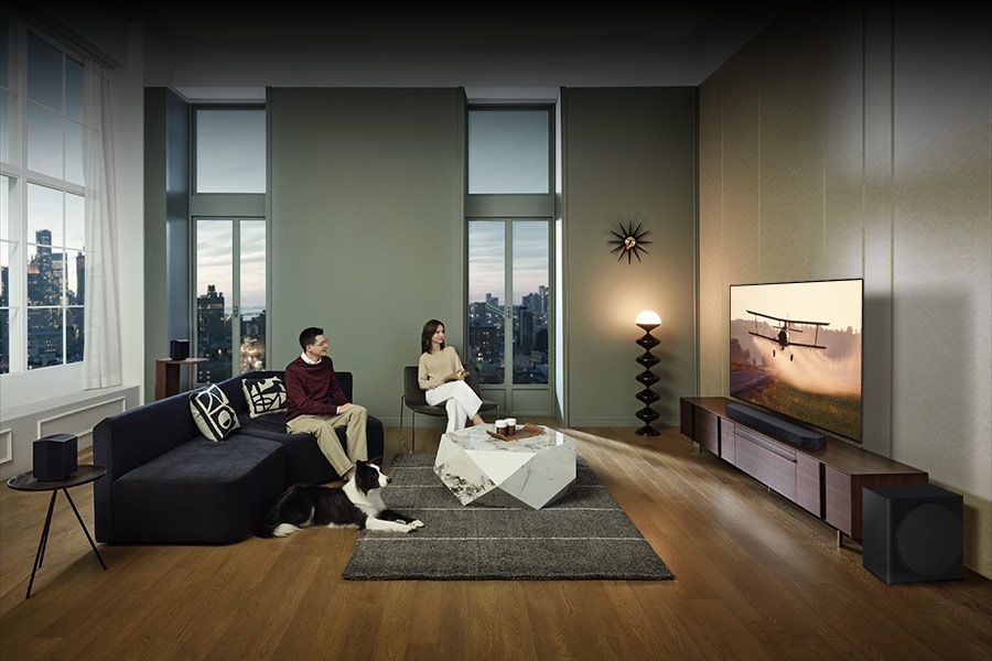 Users enjoy watching TV with Samsung Soundbar Q930C, subwoofer and rear speakers in their living room.