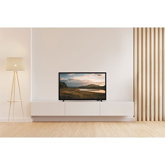 A H5000 is placed on the TV cabinet in a living room. The screen displays a stunning sunset over a serene lake and mountains.
