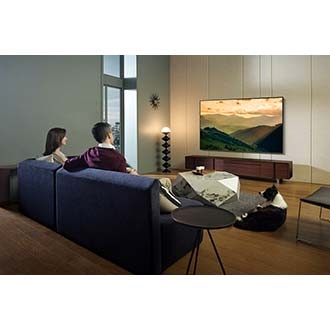 2 people and a dog is watching a movie on the QLED TV.