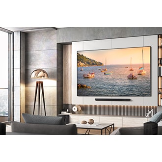 A 98 inch QLED TV hangs on the wall, showcasing a picturesque view of numerous boats sailing on the sea. Below the TV, a soundbar is installed.