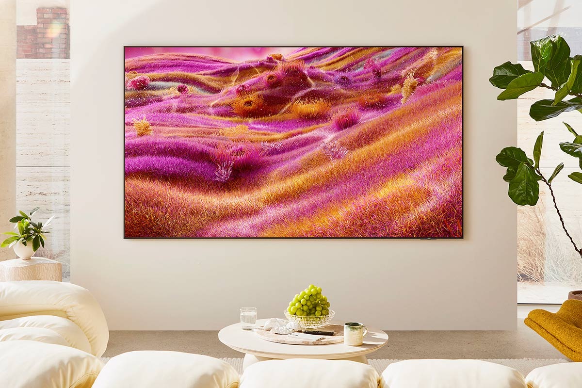 A Neo QLED TV is installed on the wall of a sunny room. The screen displays a colorful abstract landscape.