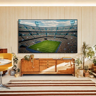 A UE100F is installed on the wall of a living room. It depicts a scene of a crowded stadium in vivid colors.
