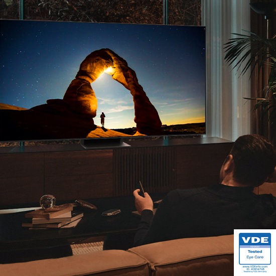 A man is watching his QLED TV at night with the screen optimally adjusted in EyeComfort mode.