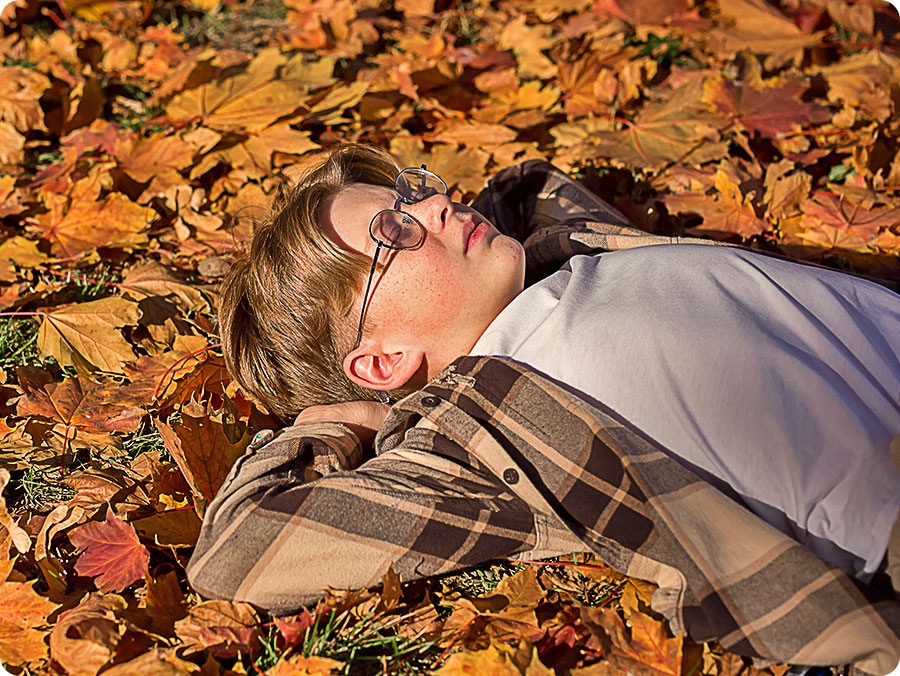 Image of a little boy laying on the ground covered in fall leaves. Several differents points are detected, including the boy's face, hair, clothes and leaves, and then upscaled to 4K resolution, along with the rest of the image. The result is a much sharper image where subtle details are visible.