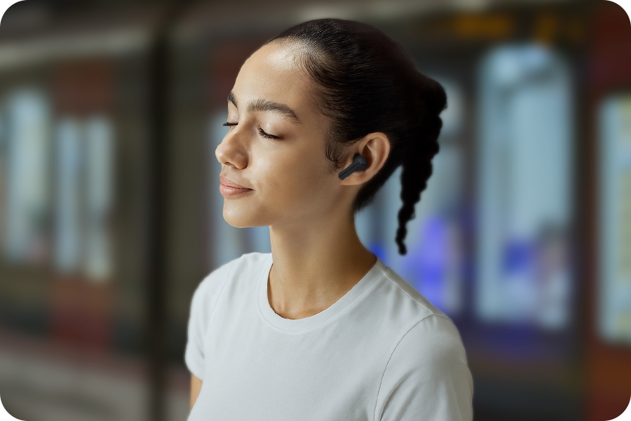 A woman wearing Black Galaxy Buds3 FE in an urban setting.