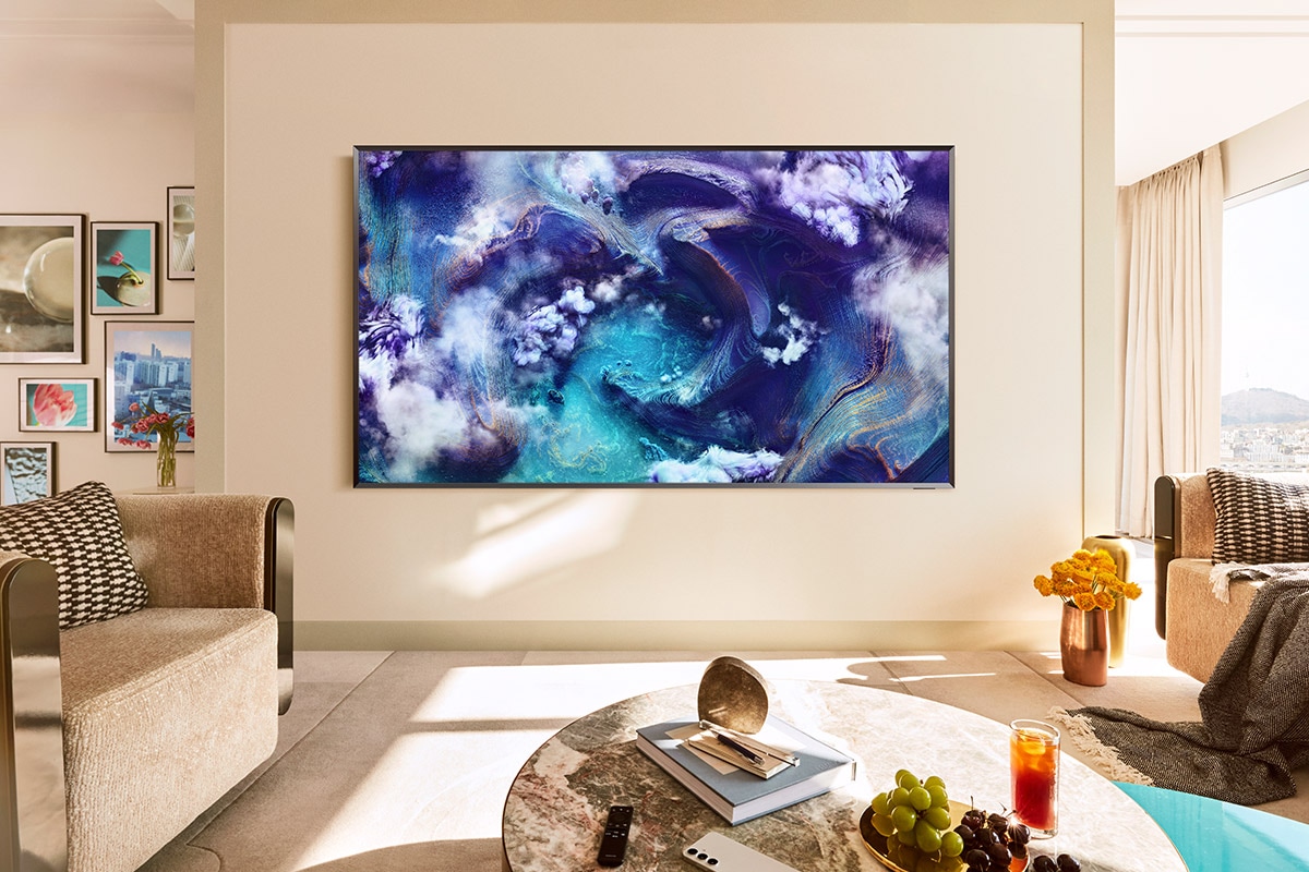 A Neo QLED TV is installed on the wall of a living room. It displays a vivid blue waves on screen.