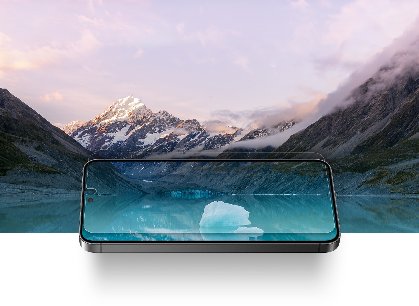 Galaxy S24 z antyrefleksyjną folią ochronną jest nałożony na zaśnieżony krajobraz gór i jeziora. Przejrzystość krajobrazu można zobaczyć przez przezroczystą jak soczewka osłonę ekranu.