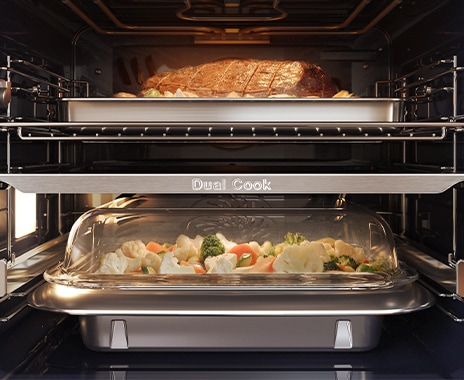 Shows the inside of the oven with a joint of meat roasting in the top zone and vegetables being steamed in the lower zone.