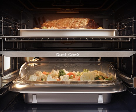 Afișează interiorul cuptorului cu un rost de carne prăjită în zona superioară și legumele coapte la abur în zona inferioară.