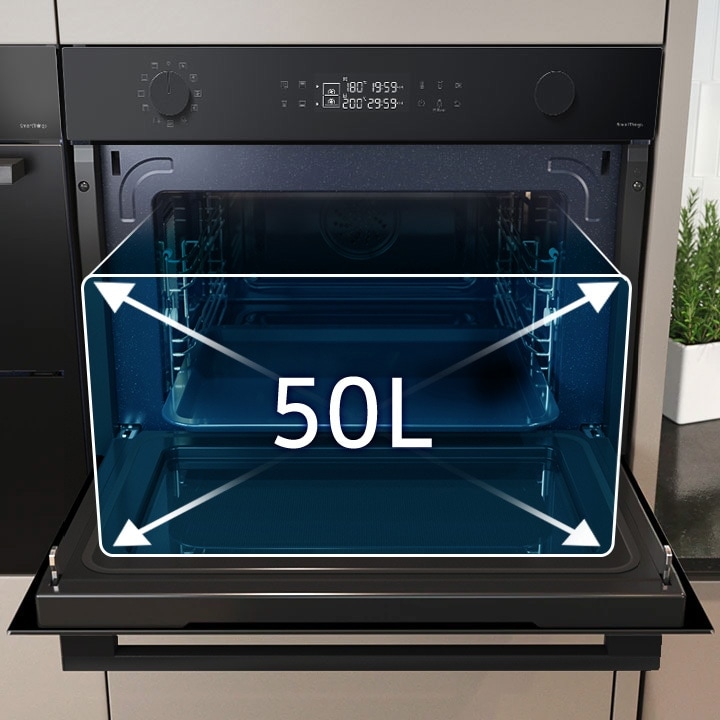 Shows a large tray of food cooking inside the spacious oven with arrows illustrating its 50 liter capacity.