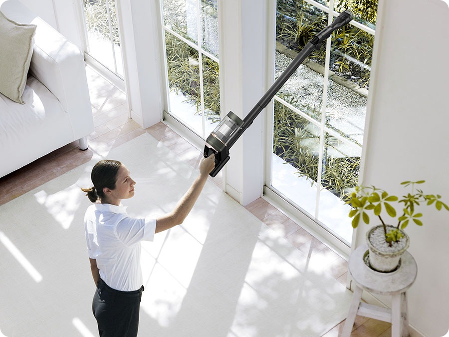 A woman vacuums a high window sill with a Bespoke Jet Plus.