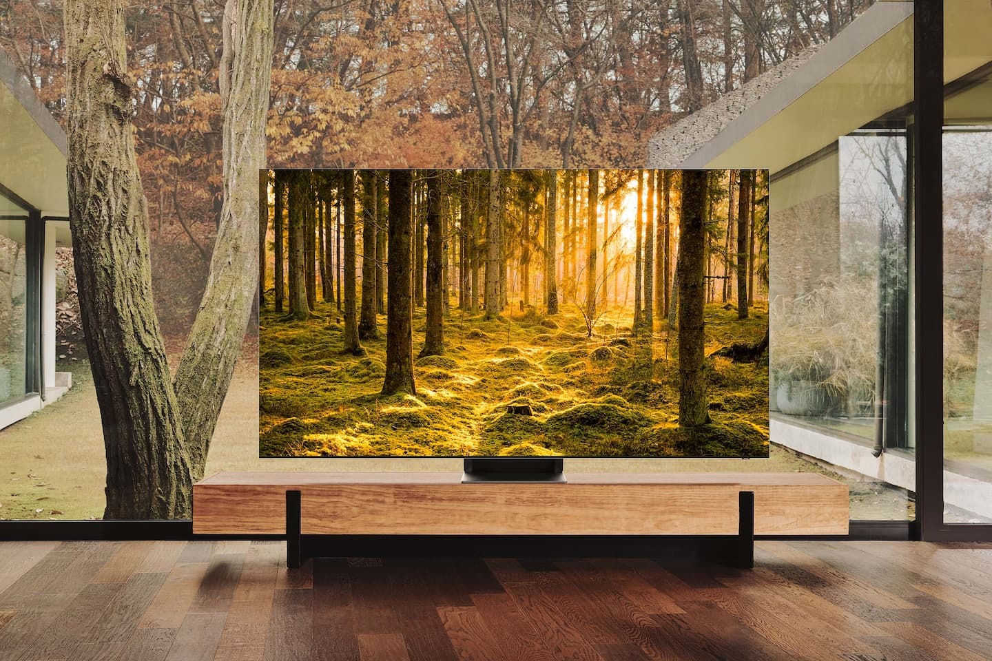 Telewizor QLED 8K Excellence Line Samsung na szafce stojący na tle okna z widokiem na las