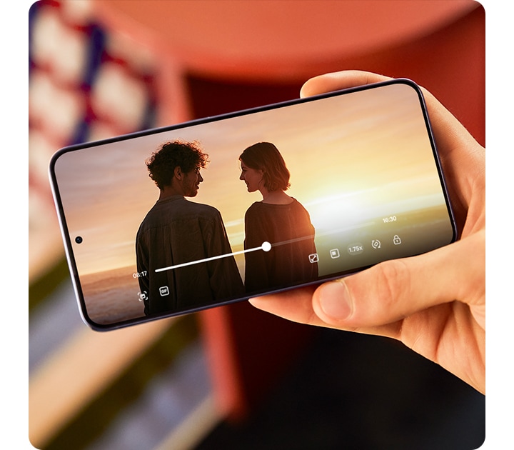 Galaxy S24 Plus se sostiene en el exterior a la luz del sol. En la pantalla se reproduce un video con colores intensos y alto contraste.