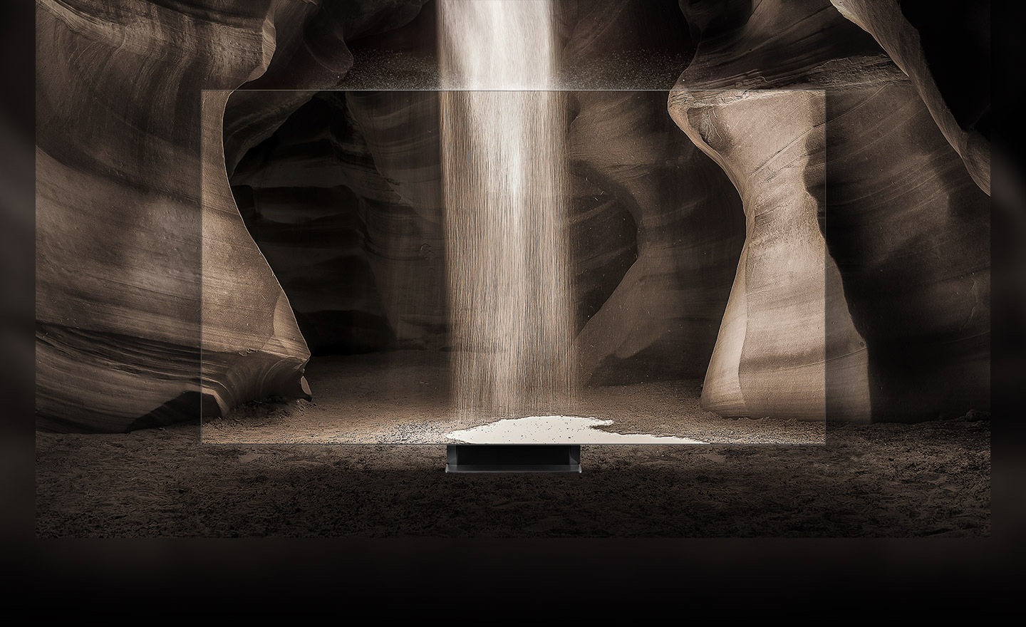 Nisipul cade la pamant in natura.  Un ecran infinit fara rama se afla in centru, ilustrand aceeasi imagine.